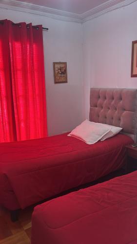 a bedroom with two beds and a red curtain at Hostal Estadio Nacional in Santiago