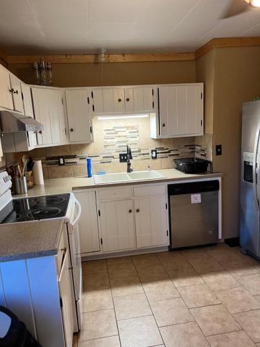 a kitchen with white cabinets and a sink and a refrigerator at Chinook Winds Lodge in Dubois