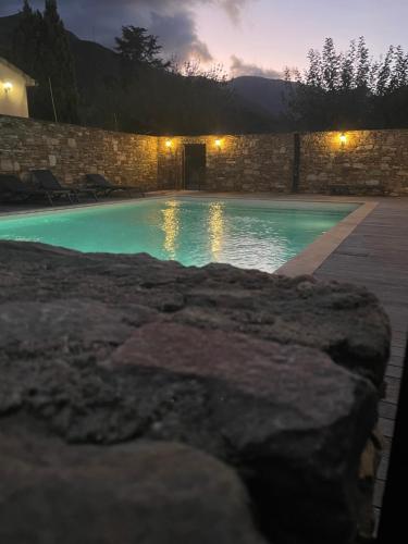 a swimming pool at night with a stone wall at La Casa ISAIA, Cap Corse in Sisco