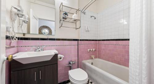 a pink bathroom with a sink and a tub and a toilet at EMBASSY HOTEL in San Francisco