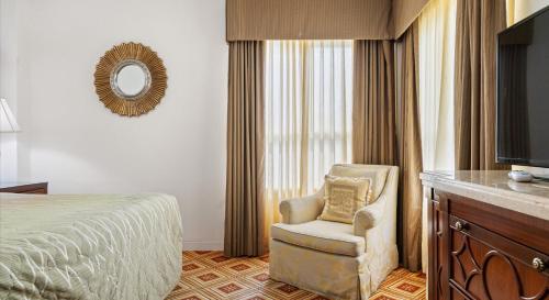 a bedroom with a bed and a chair and a mirror at EMBASSY HOTEL in San Francisco