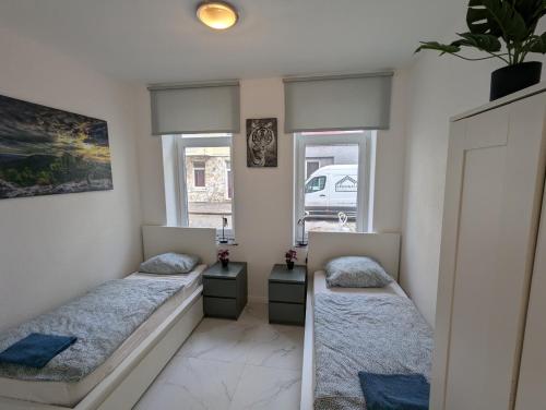 zwei Betten in einem Zimmer mit zwei Fenstern in der Unterkunft Nord-Apartment 5 I 1 Zimmer mit einladendem Wohnbereich im Erdgeschoss in Bremerhaven