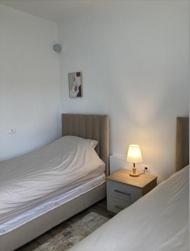 a bedroom with two beds and a lamp on a night stand at Hadri-rooms in Korçë