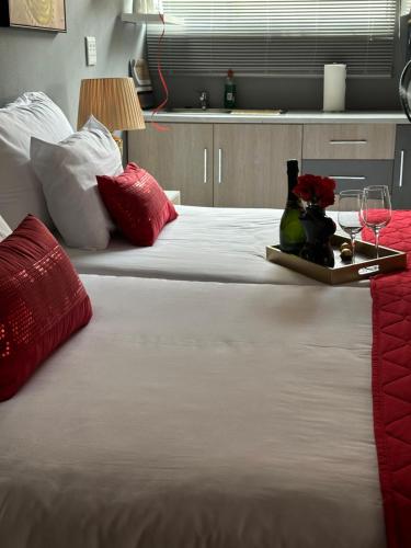 una gran cama blanca con una bandeja con copas de vino y un pájaro en ella en Serenity on Sabie, en Vanderbijlpark