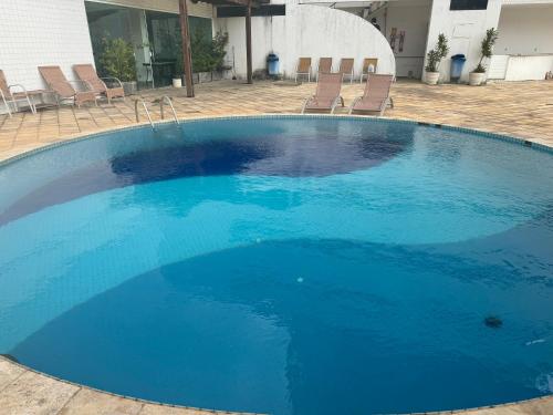 una grande piscina blu con sedie di fronte a un edificio di Apartamento Novo Renascença Vista Lagoa a São Luís