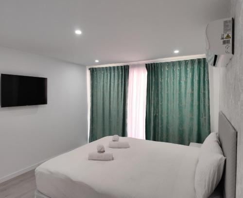 1 dormitorio con cama, TV y cortinas verdes en Mediterranean Stays Platinum, en Alicante
