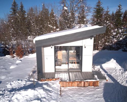un petit bâtiment dans la neige avec des arbres enneigés dans l'établissement Cottage contemporain Cosy & Chic, à Prémanon