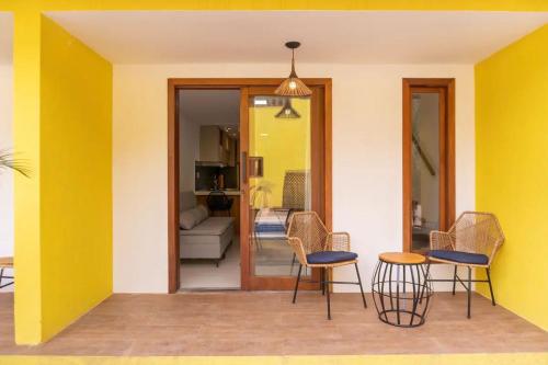 a living room with yellow walls and chairs and a table at Morro de São Paulo- Quarta Praia - Casa Bethel in Cayru