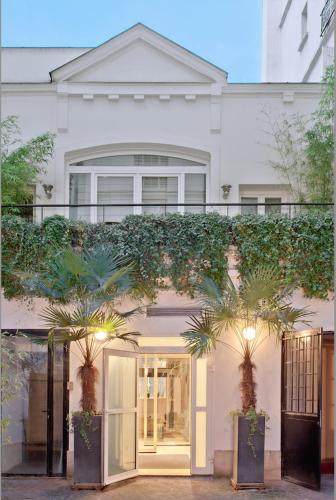 une maison blanche avec des palmiers devant dans l'établissement Luxury Two-Story Designer Loft in Paris Epicenter - Bright and Spacious, à Paris