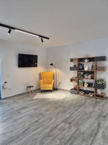 an empty living room with a yellow chair and a tv at Casa de Vacanta Magherus in Topliţa