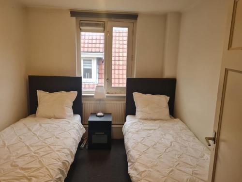 zwei Betten in einem kleinen Zimmer mit Fenster in der Unterkunft Three bedroom lovely apartment in Oosterbeek