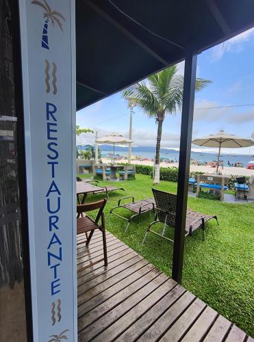 a porch with a table and chairs and a field of grass at Hotel Sete Ilhas in Florianópolis