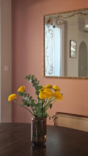un vase rempli de fleurs jaunes assises sur une table dans l'établissement La Maison de Jeanne, à Narbonne