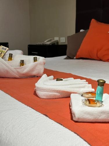 two beds with towels and a bottle on them at Hotel Gya Boutique in Aguascalientes