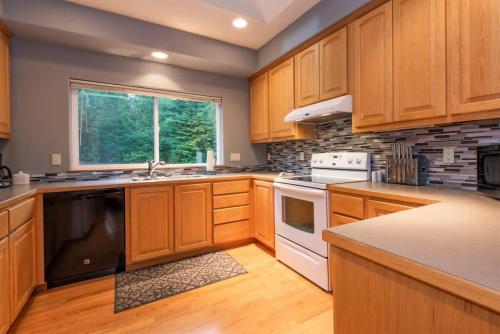 a large kitchen with wooden cabinets and a window at PA Whispering-Pines in Port Angeles