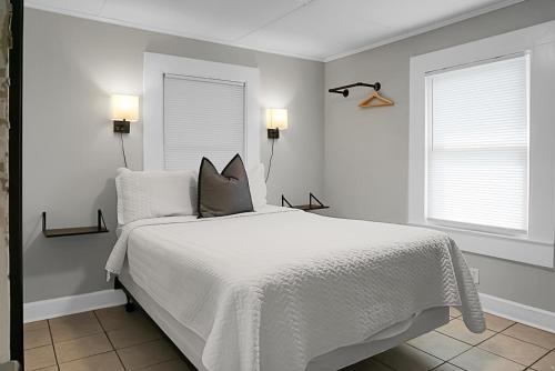 a bedroom with a white bed and two windows at Seabirds Motel At Kure Beach in Kure Beach