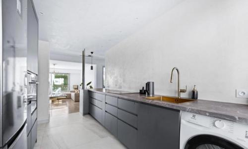 une cuisine blanche avec un évier et une machine à laver dans l'établissement Le Royal, à Cannes