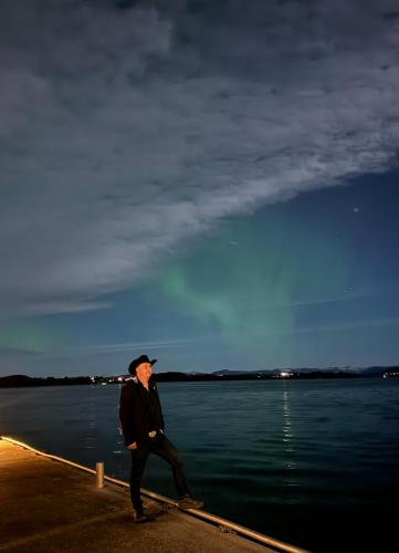 a man standing next to a body of water at Sjøberg Hotell og Ferie Leiligheter in Østhusvik