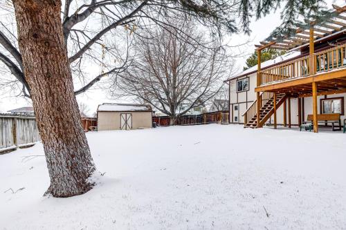 a snow covered yard with a tree and a house at Fenced Yard, Patio Family-Friendly Pocatello Home in Pocatello