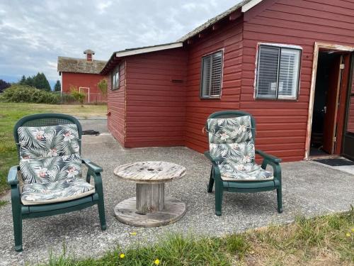 two chairs and a table in front of a red building at SQ The-Crab-Shack in Sequim