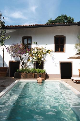 a man in a swimming pool in front of a house at Batucada Hotel Boutique in Valle de Bravo
