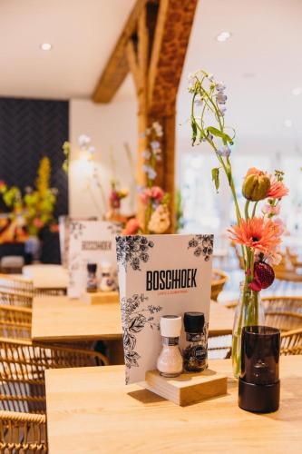 a sign on a table with a vase of flowers at Hotel & Brasserie De Boschhoek in Oostkapelle