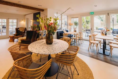 a table and chairs with a vase of flowers on it at Hotel & Brasserie De Boschhoek in Oostkapelle