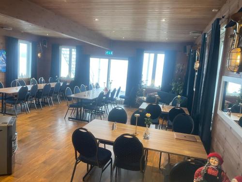 a restaurant with wooden tables and chairs and windows at Sjøberg Hotell og Ferie Leiligheter in Østhusvik
