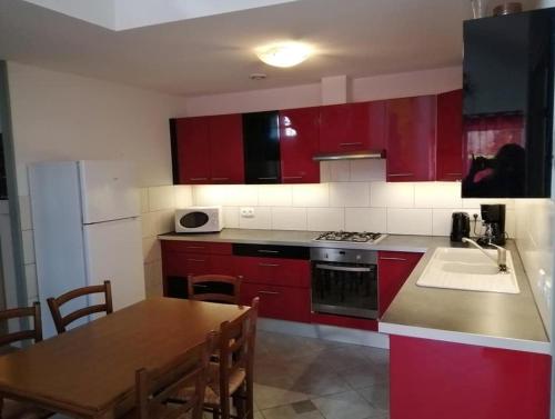 a kitchen with red cabinets and a table and a sink at Sports et détente in Fresse