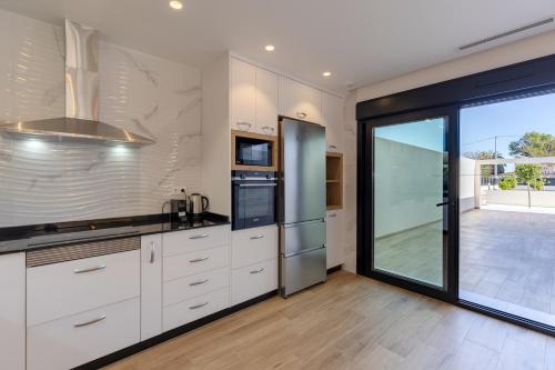a kitchen with white cabinets and a large window at Palm Breeze Villa by Fidalsa in Catral