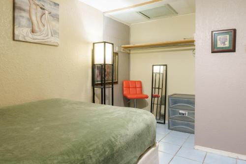 a room with a bed and a red chair at Bridgetown suites in El Paso