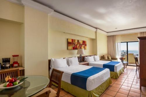 a hotel room with two beds and a table at Royal Villas Resort in Mazatlán