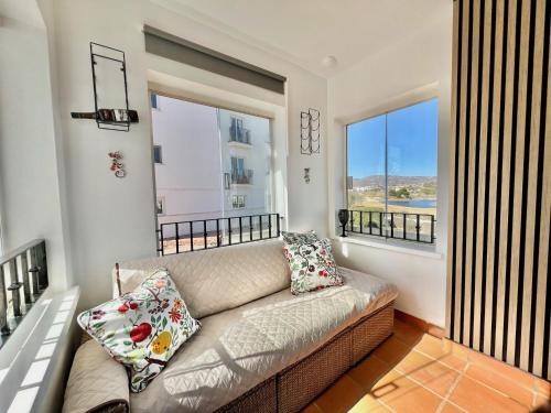 Una sala de estar con un sofá y dos ventanas. en Stunning front line apartment with golf and mountains view, en Sucina