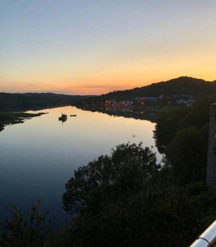 a river at sunset with a boat in the water at White Heather House Clifden Town Square in Clifden