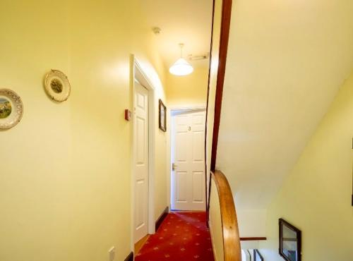 a hallway with a red floor and a white door at White Heather House Clifden Town Square in Clifden
