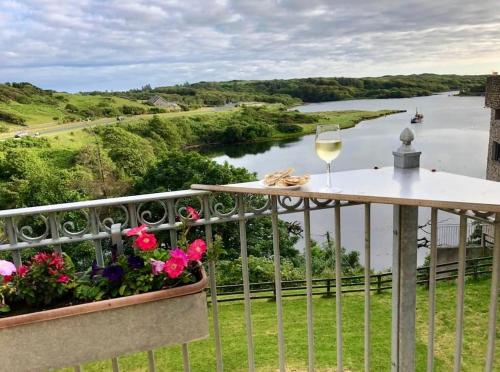 a glass of wine on a balcony overlooking a river at White Heather House Clifden Town Square in Clifden