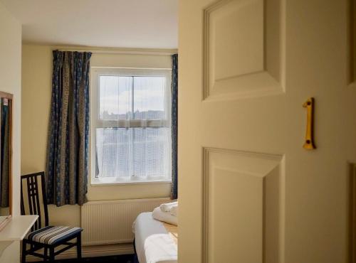 a bedroom with a bed and a window and a chair at White Heather House Clifden Town Square in Clifden