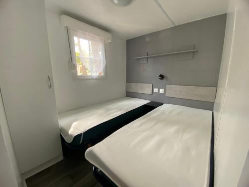 deux lits dans une petite pièce avec une fenêtre dans l'établissement Mobil Home Bungalow Camping Sables D Or, au Grau-dʼAgde