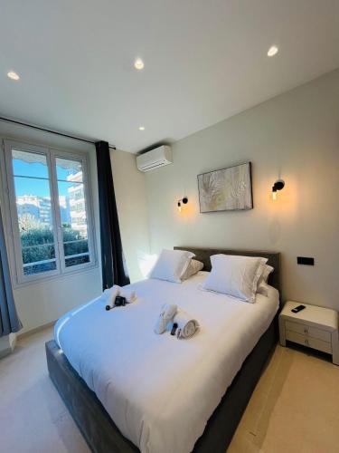 une chambre avec un grand lit avec deux animaux en peluche dessus dans l'établissement 3 pièces en cœur de cannes, à Cannes