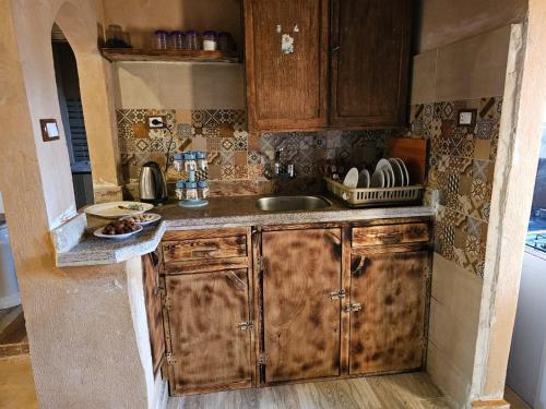 a kitchen with wooden cabinets and a sink at Paradise in a palm forest with epic pool in siwa oasis