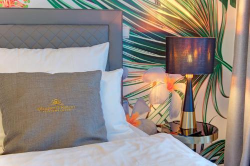 a bed with a pillow and a lamp on a side table at Blumen(t)raum Ferienwohnung 2 in Karlsruhe