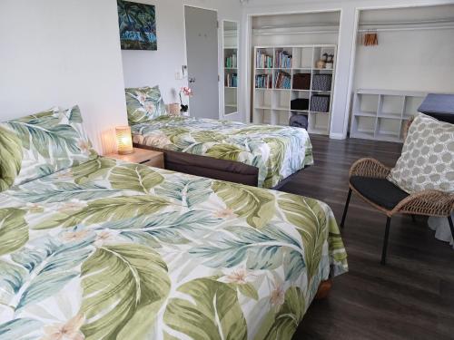 a bedroom with two beds and a chair at Coastal Retreat Holiday Home Rarotonga in Oneroa