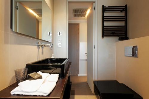 une salle de bain avec un lavabo noir et un miroir dans l'établissement Le Riviera - Cannes - Croisette - Casino, à Cannes