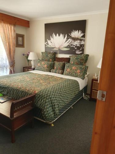 a bedroom with a large bed with a green comforter at Heavenly Farm B & B Tasmania in Boat Harbour