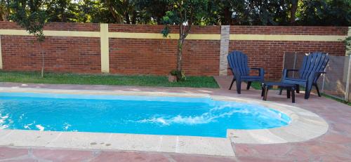 a pool with two chairs and a table next to a brick wall at Residencia céntrica Los crespones in San Ignacio