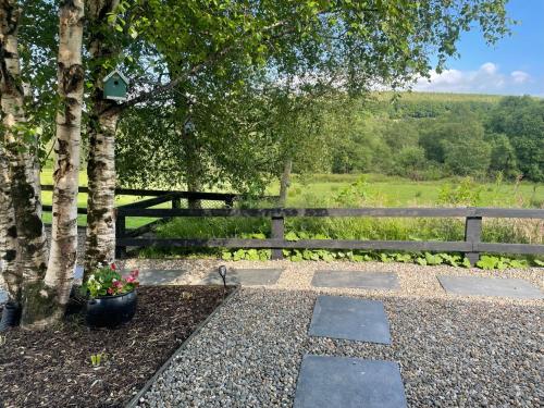 a stone walkway next to a fence with a tree at Birch Valley Accommodation Tinahely Wicklow Ireland in Killicreny Bridge