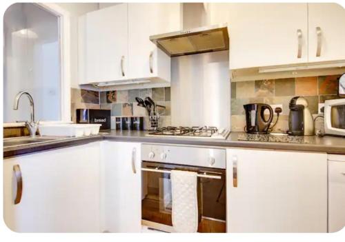 a kitchen with white cabinets and a stove top oven at Stonehouse Apartment in Mexborough