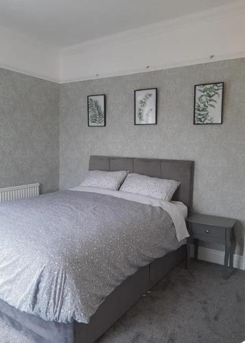 a bed in a bedroom with three pictures on the wall at Stonehouse Apartment in Mexborough