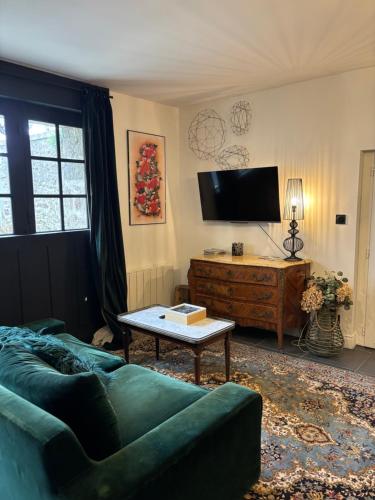 a living room with a green couch and a tv at Malouinière Guillaume Onffroy in Saint Malo