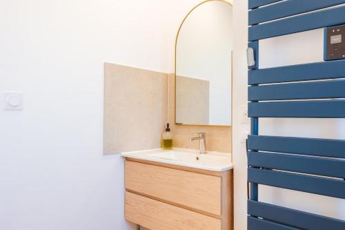 une salle de bain avec un lavabo et un miroir dans l'établissement L'escapade colorée - gare - Futuroscope - parking, à Poitiers